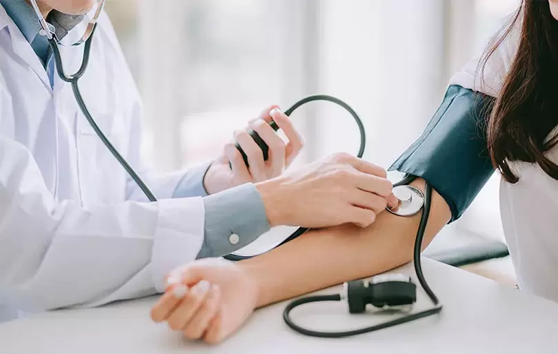 Kardiologs mēra pacienta asinsspiedienu, lai diagnosticētu hipertensiju. 